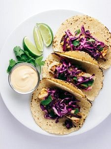 top down view of 3 grilled baja tofu tacos topped with red cabbage on a white plate