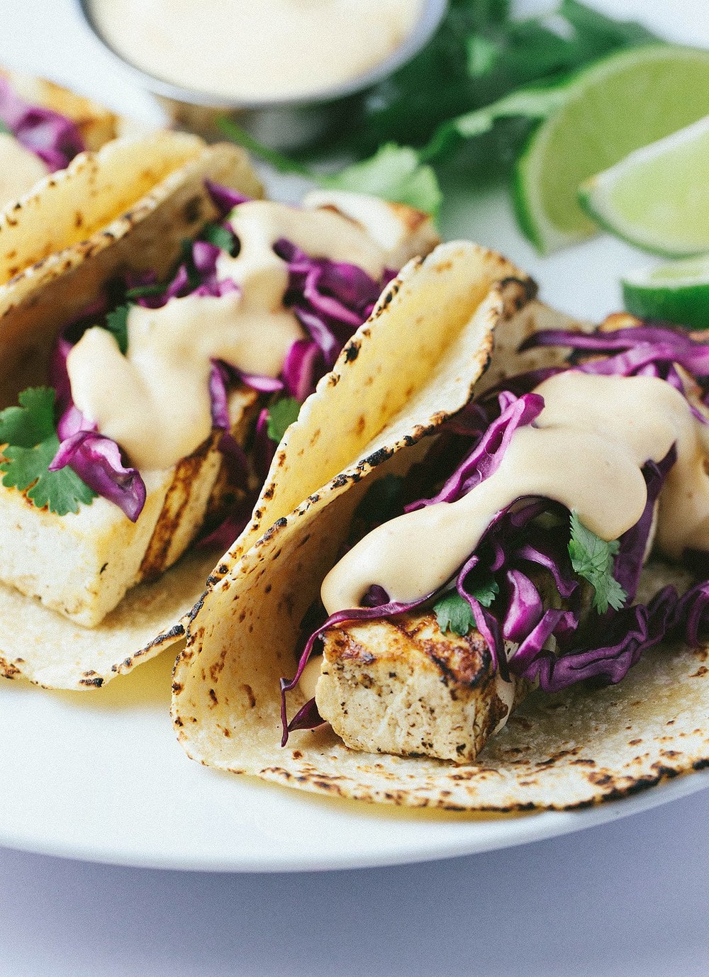 side angle view of grilled tofu taco piled high with red cabbage slaw and spicy sauce