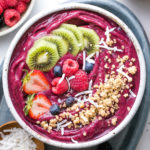 top down view of homemade acai bowl topped with healthy toppings with items surrounding.