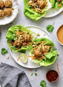top down view of vegan lettuce wraps with thai quinoa meatballs on a plate with items surrounding.