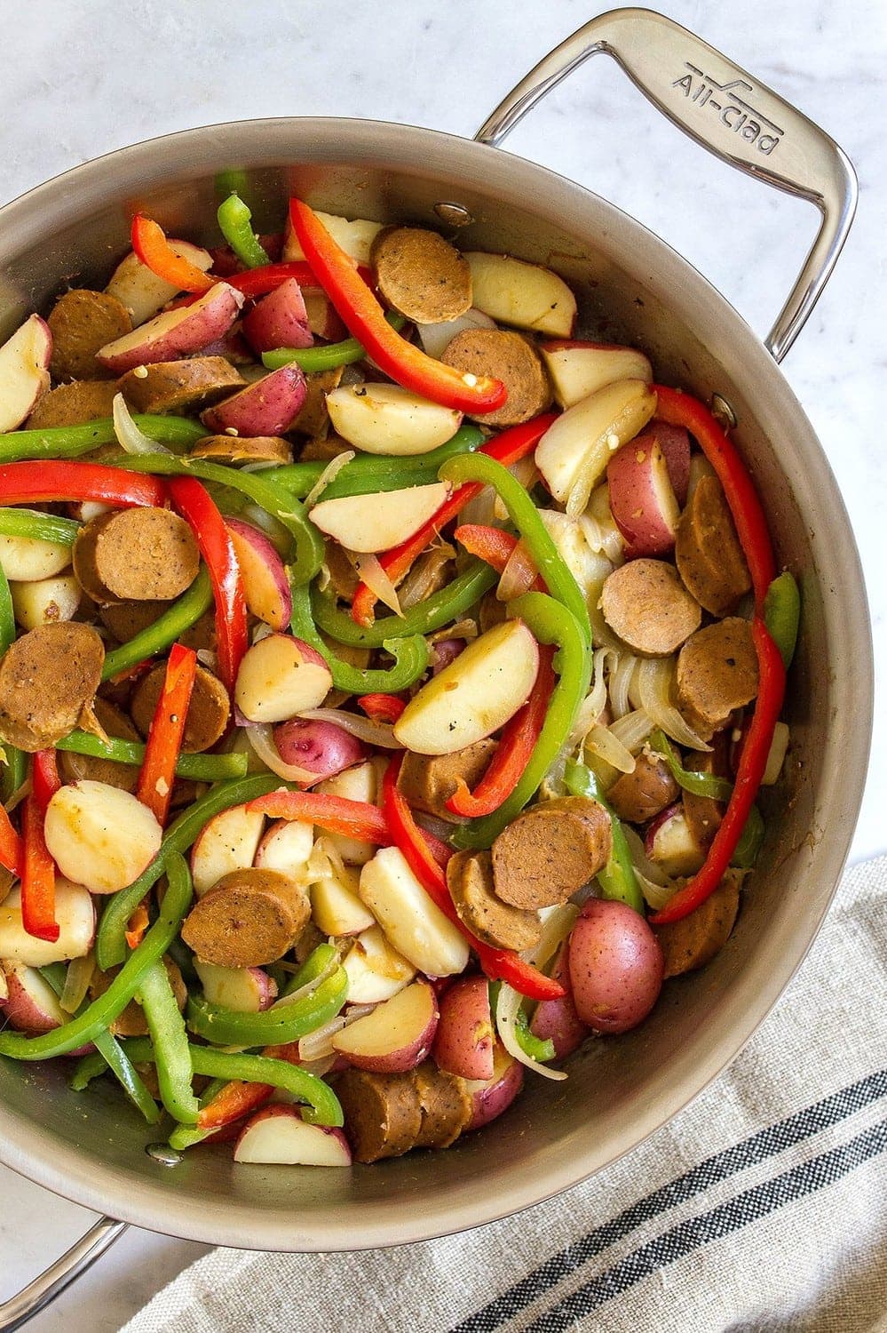 a pan with cooked sausage, peppers, potatoes and onion