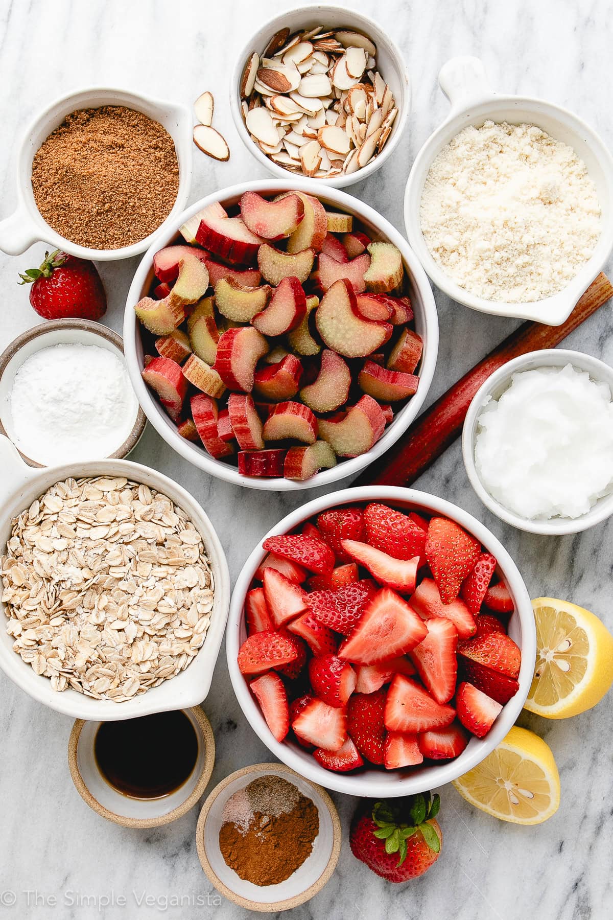 top down view of ingredients used to make strawberry rhubarb crisp on a marble slab.