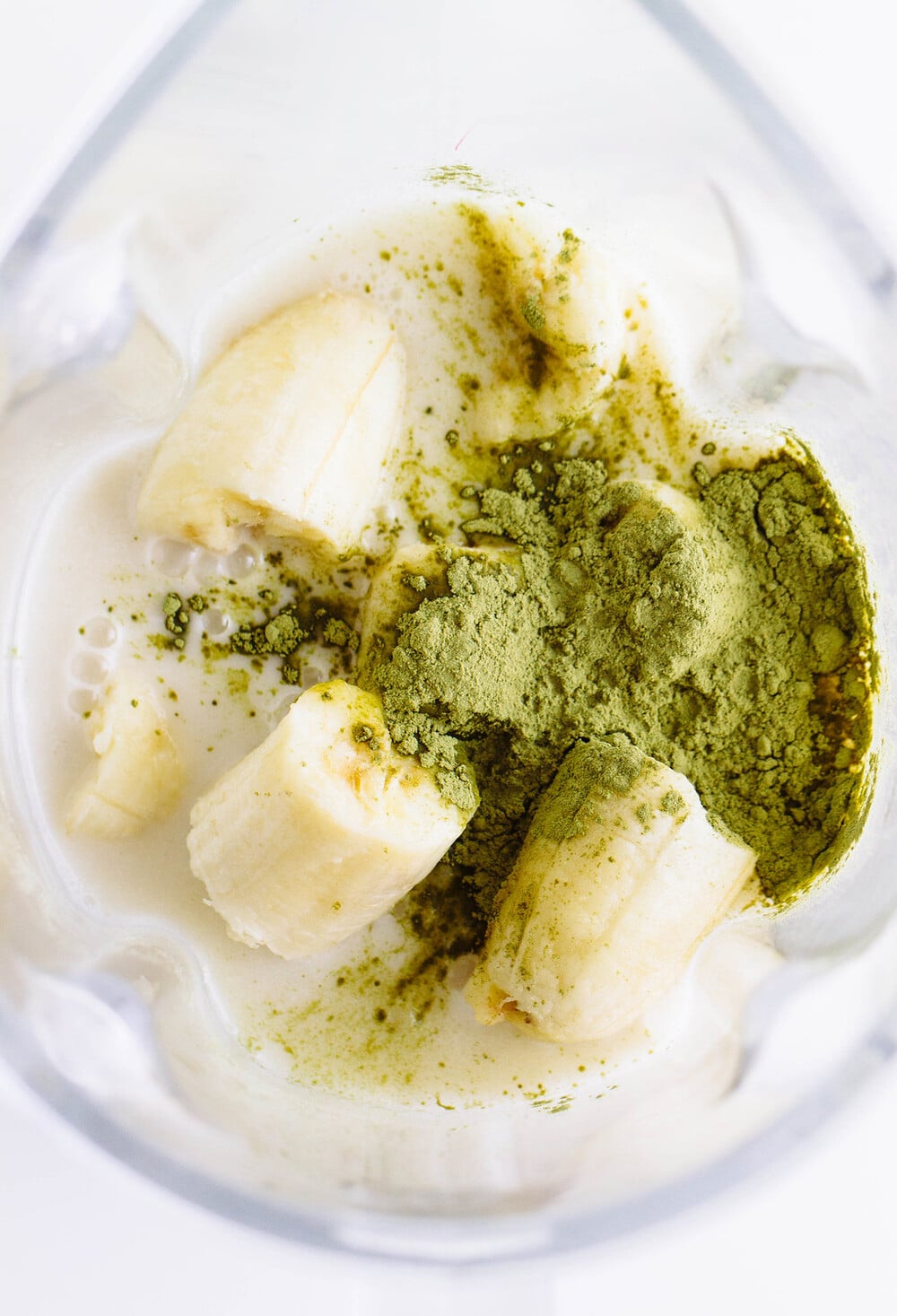 top down view of blender container filled with ingredients to make vegan matcha milkshake recipe.