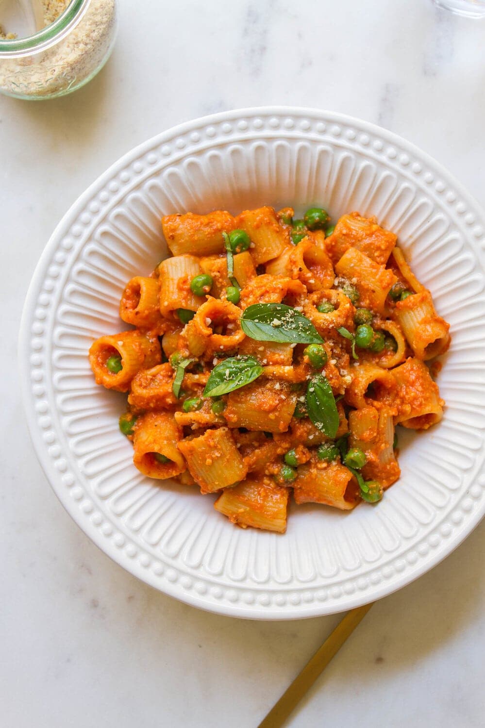 top down view of a white bowl with a hearty serving of pasta and peas with easy romesco sauce.