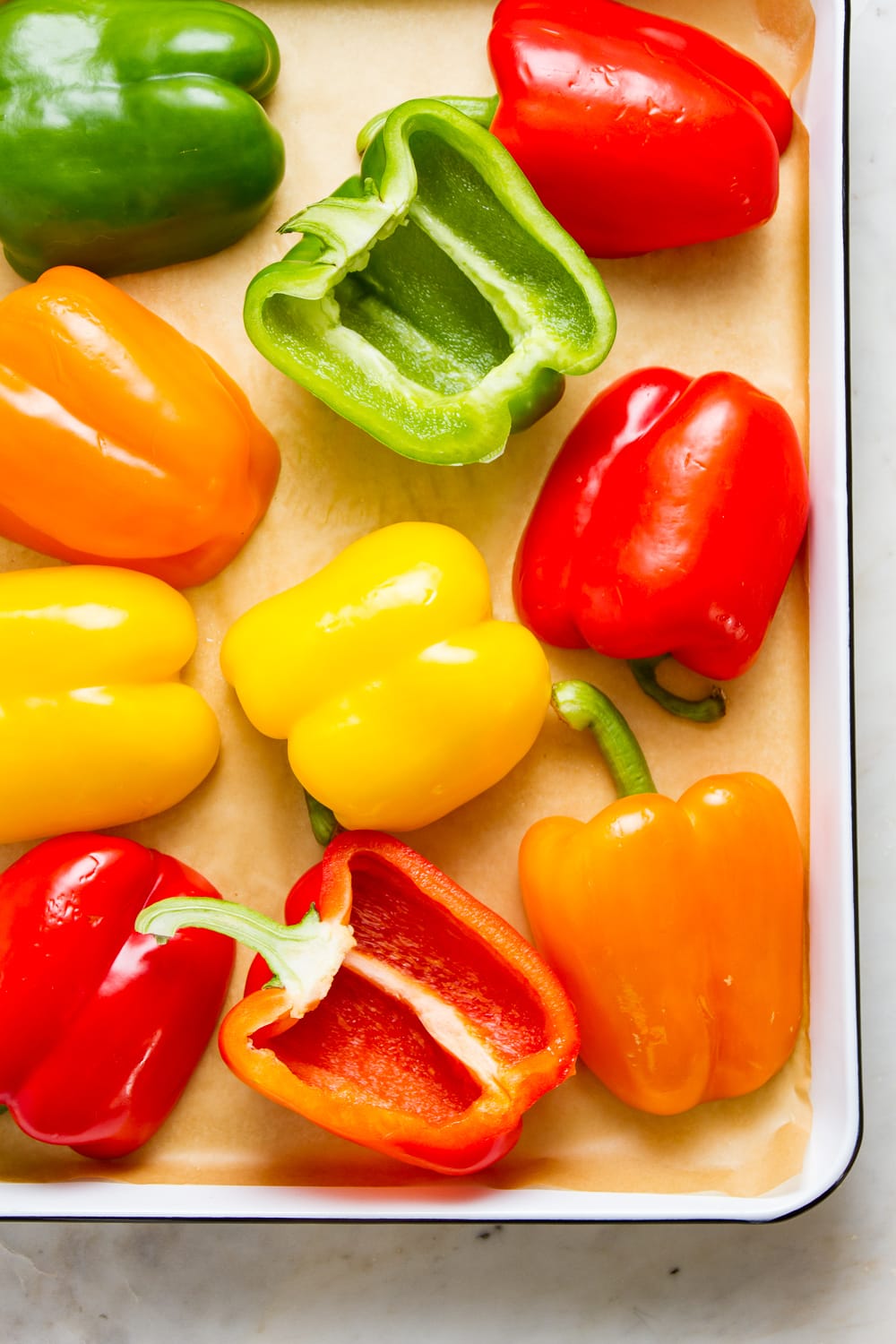 top down view of colored bell peppers cut in half and seeds removed on a baking sheet.