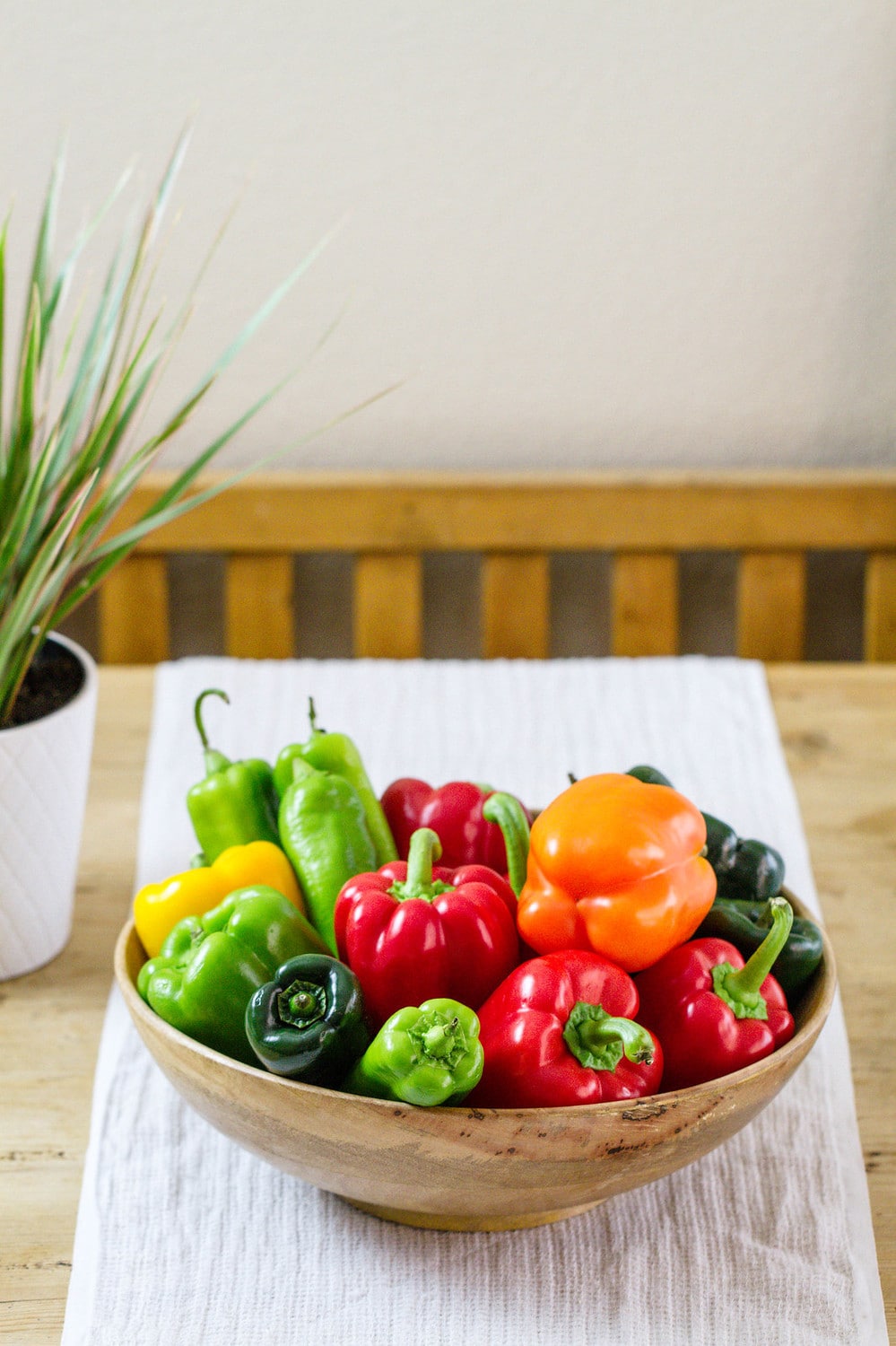 a variety of pepper in a wooden bowl on a table.