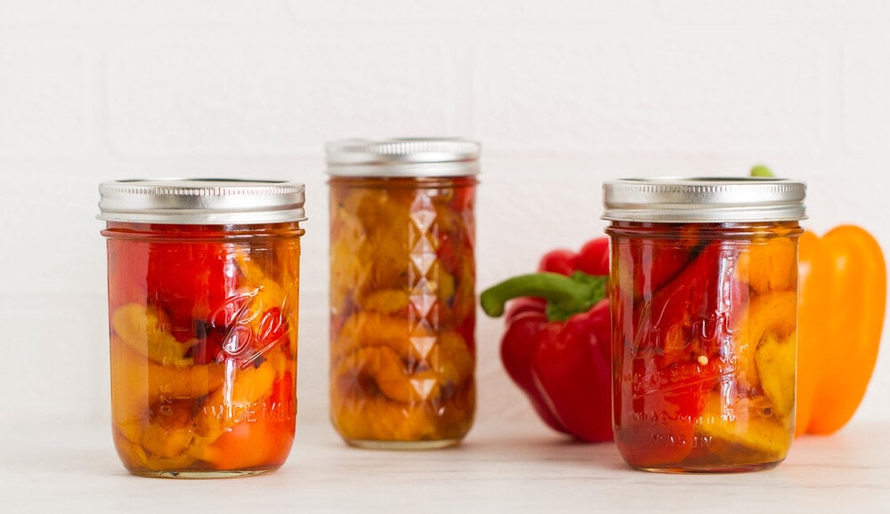 head on view of roasted red peppers in mason jars.