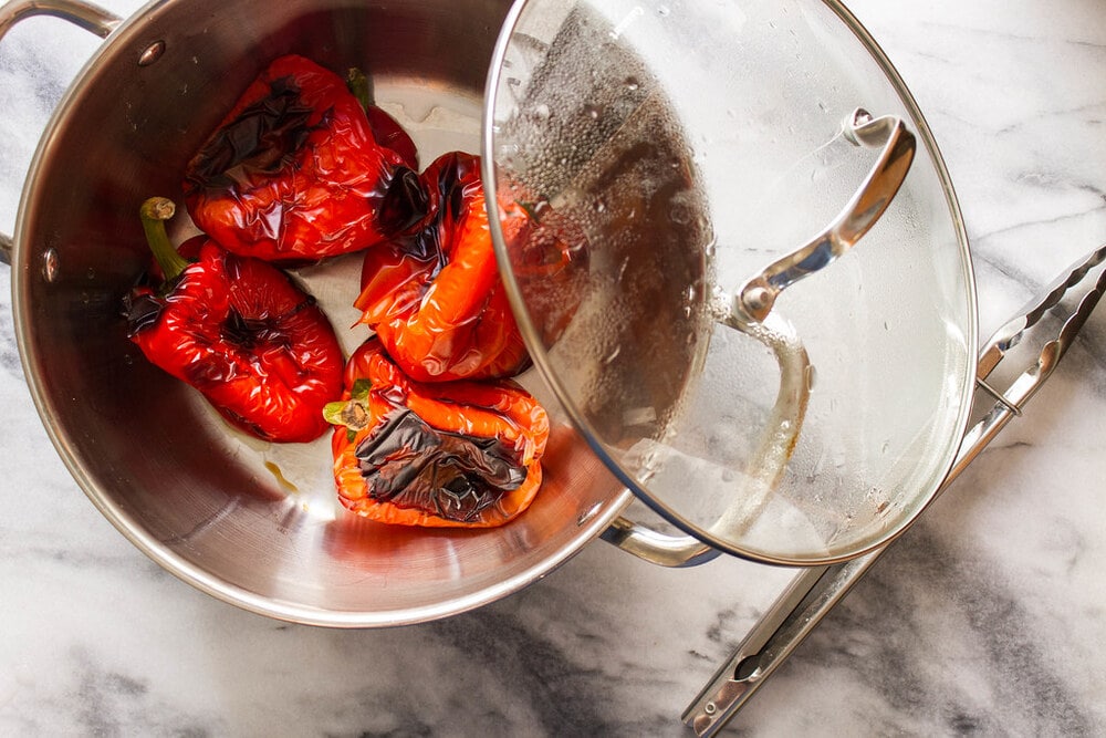 roasted bell peppers steaming in a large pot with lid.