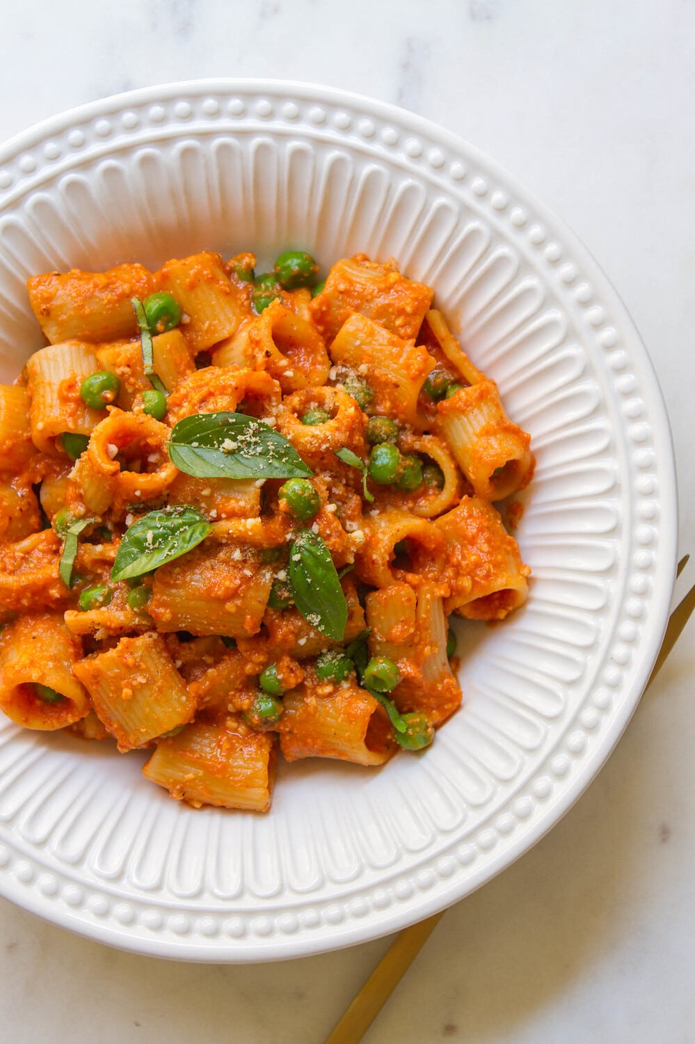 top down view of a white bowl with a hearty serving of pasta and peas with easy romesco sauce.