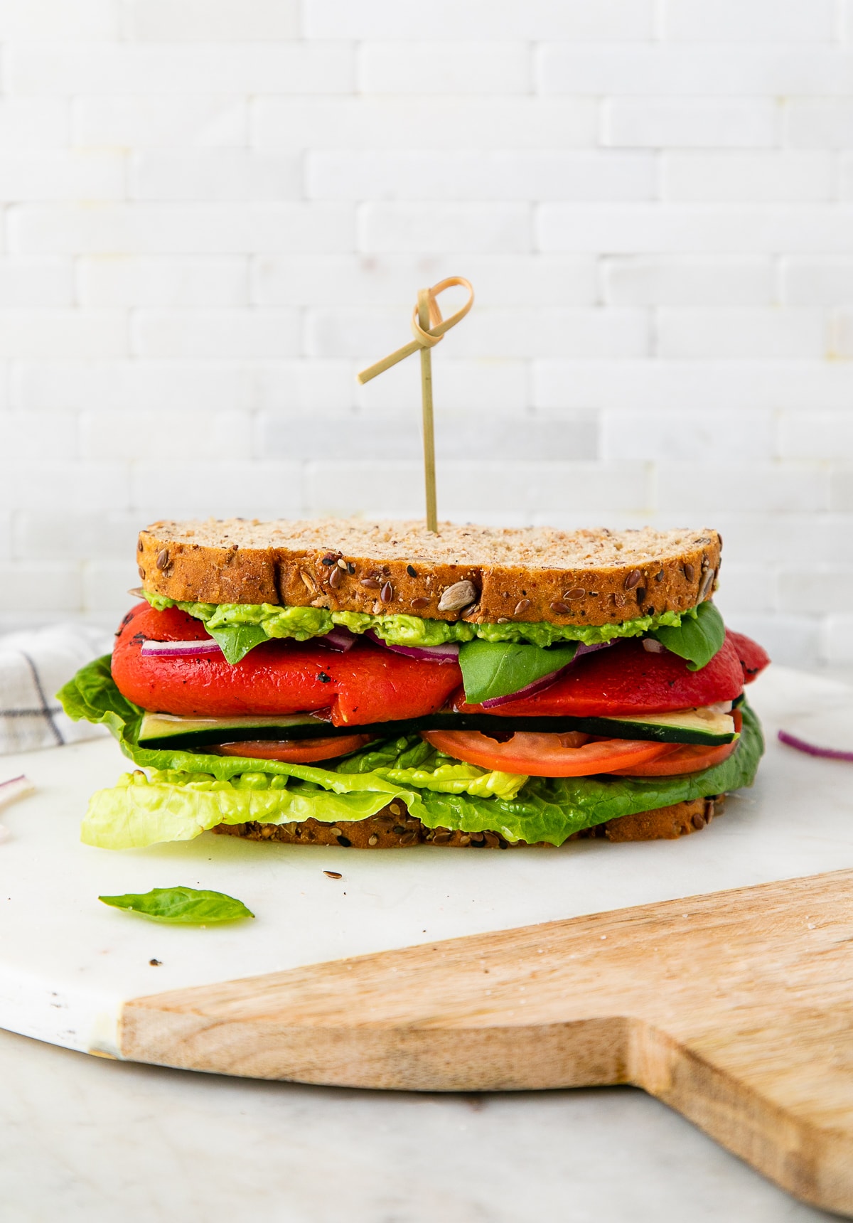 head on view of healthy mediterranean veggie sandwich with red peppers on a marble serving tray.