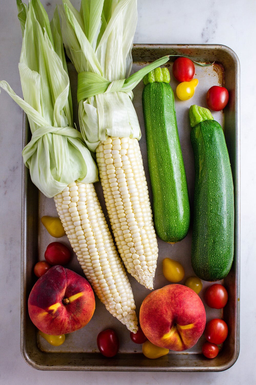 top down view of produce on a rimmed baking sheet.