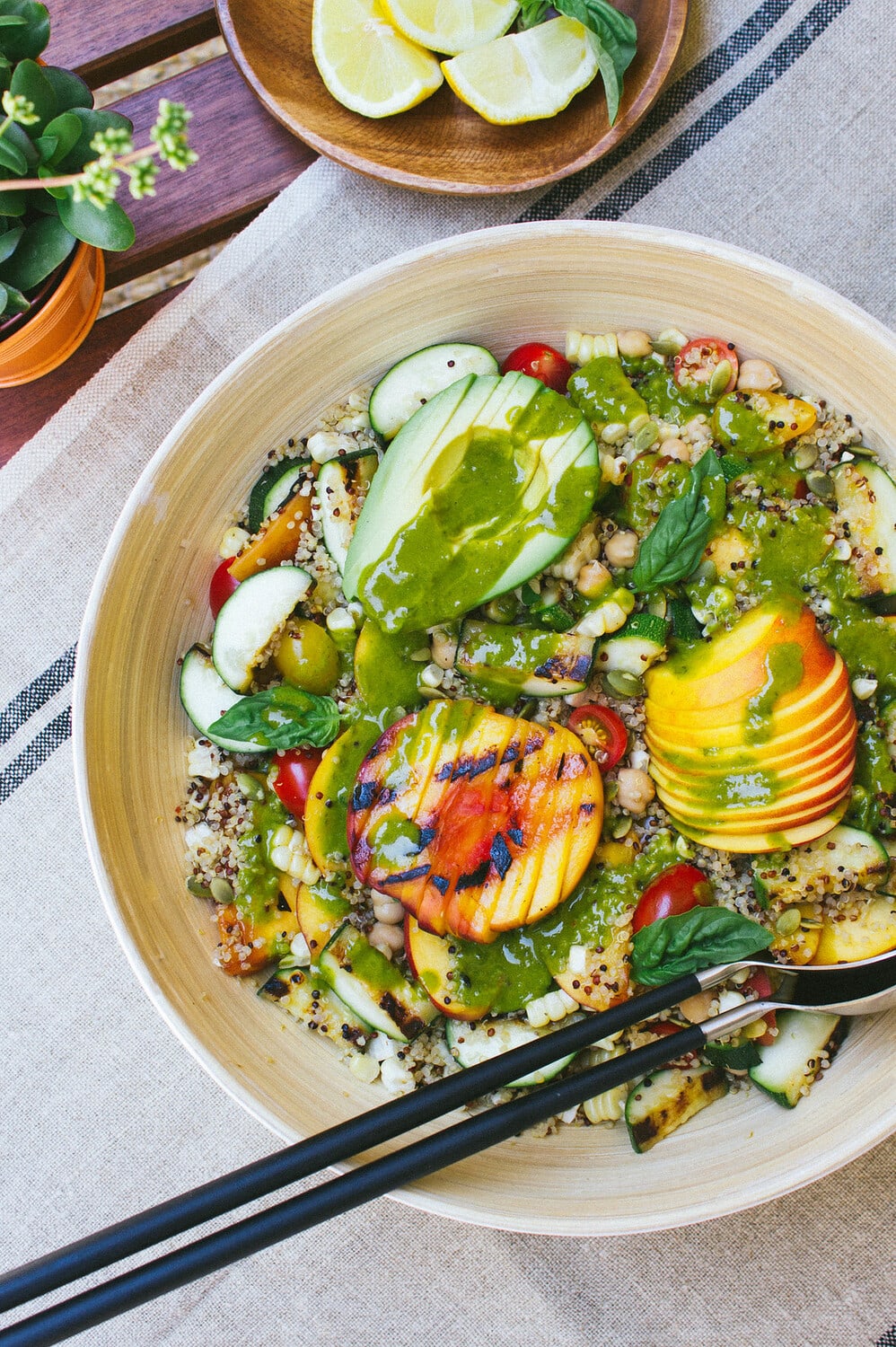 top down view of grilled peach, corn and zucchini quinoa salad with basil dressing poured over top.