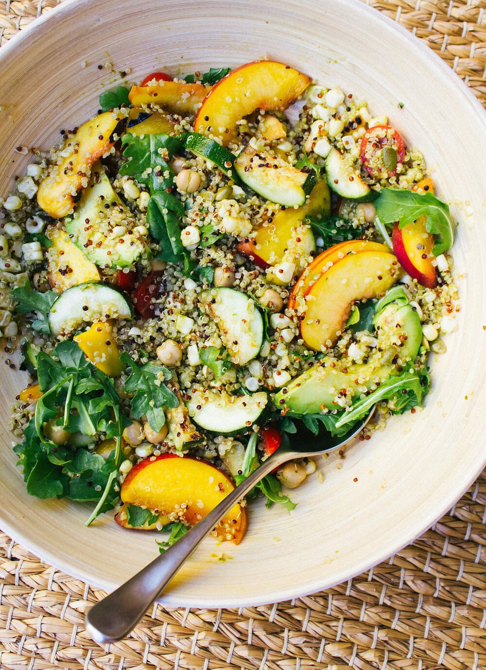 top down view of grilled peach, corn and zucchini quinoa salad mixed together in a mixing bowl.