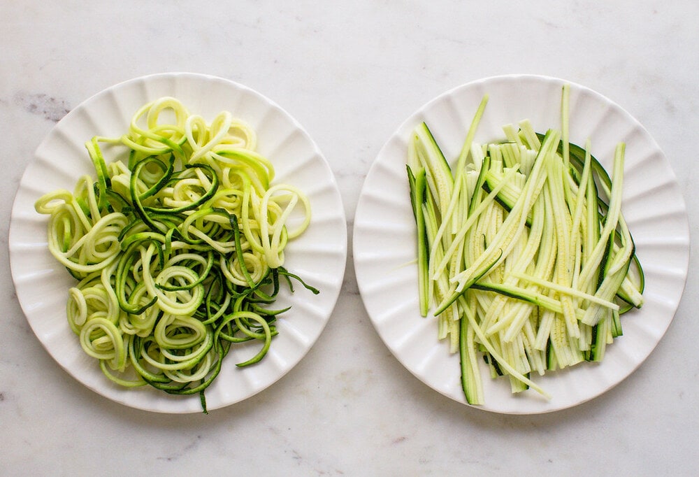 top down view of freshly sprialized and julienned zucchini noodles on a white plate.