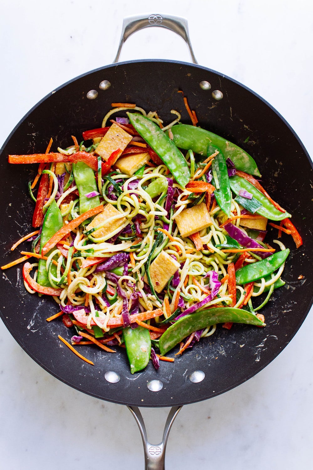 top down view of cooked thai zucchini noodle with crispy tofu in a wok.