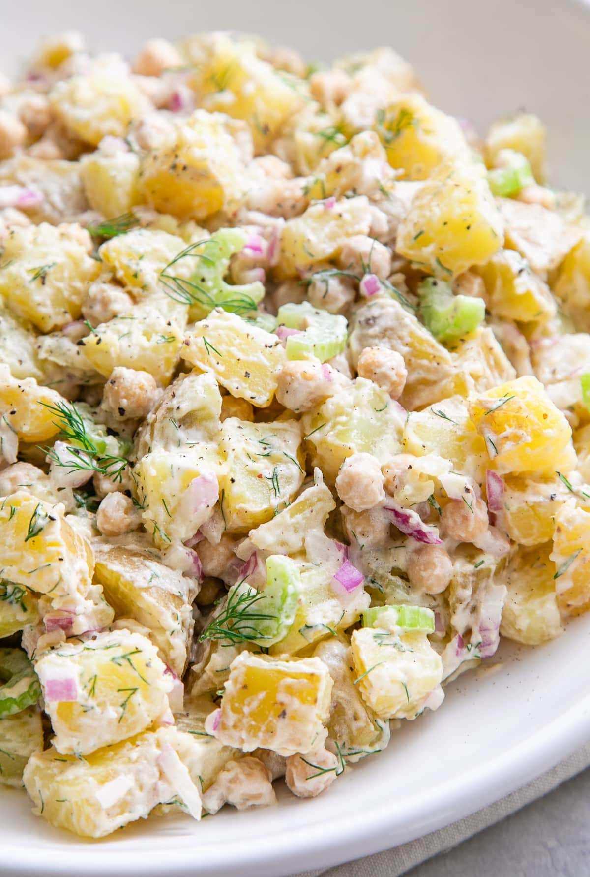 side angle view of creamy dill potato salad in a white bowl.