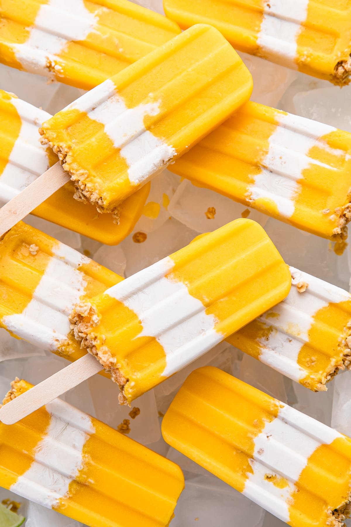 top down view of coconut mango popsicles arranged on tray with ice.