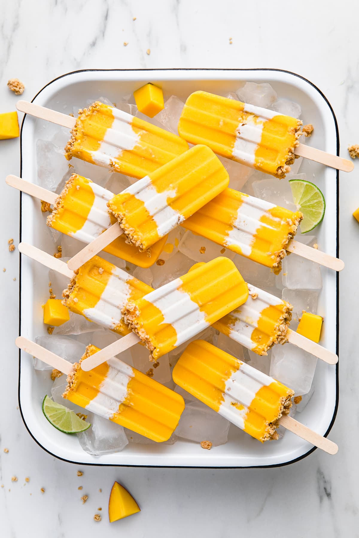 top down view of coconut mango popsicles arranged on tray with ice.