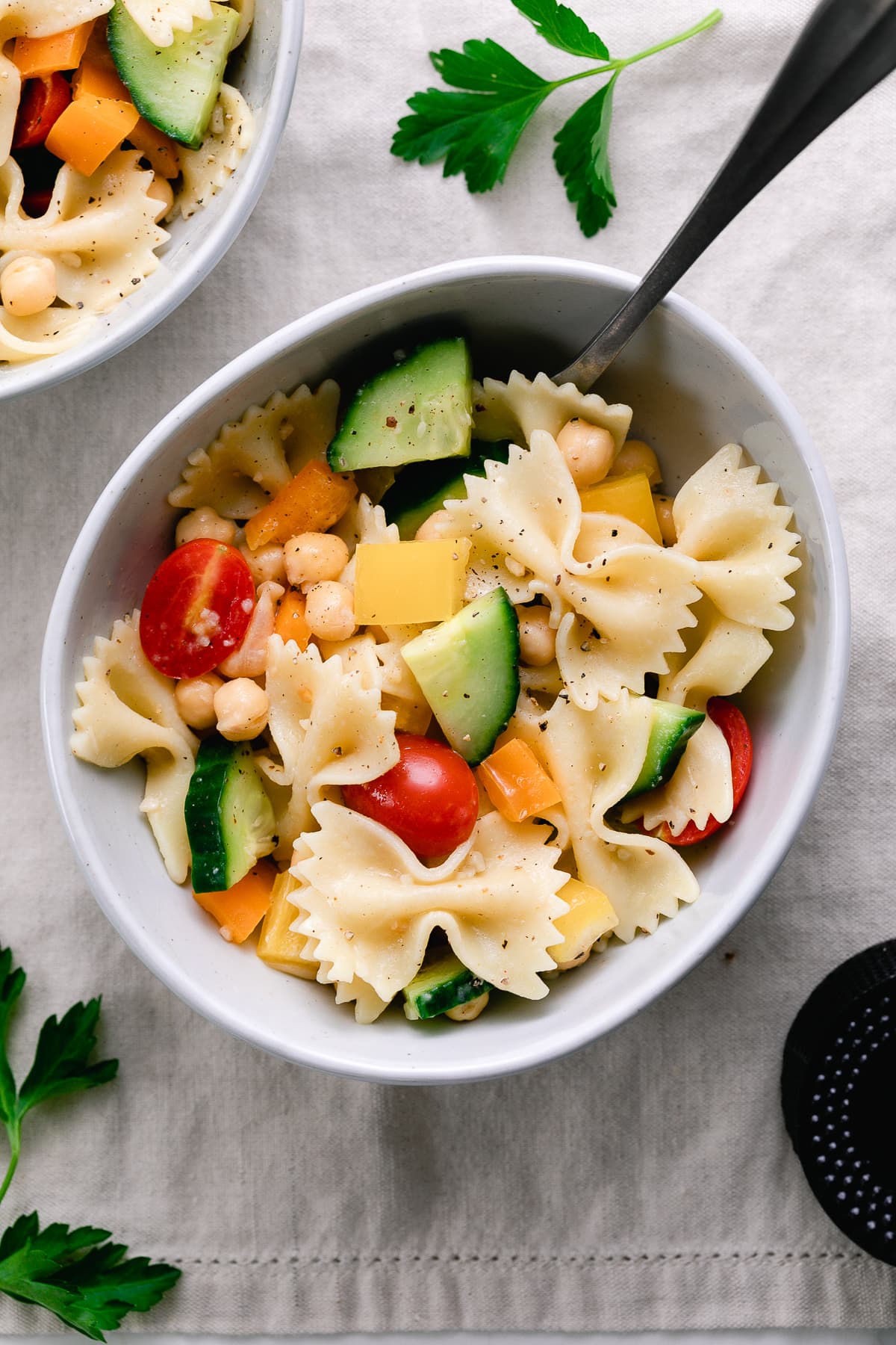 top down view of healthy pasta salad in a bowl with items surronding.