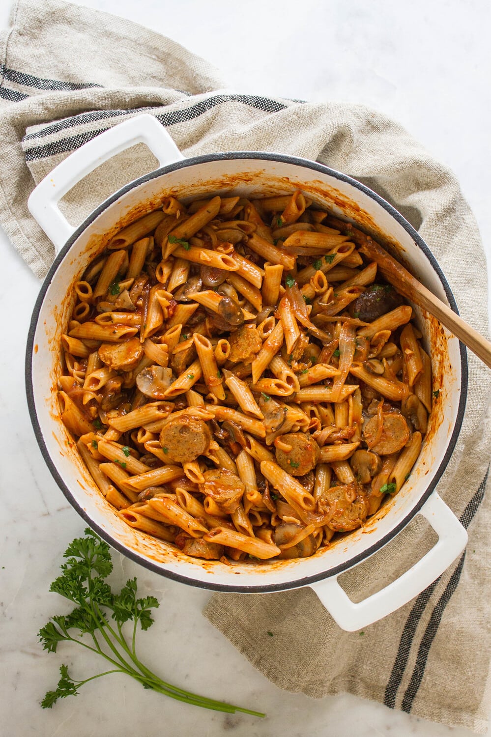 top down view of one pot penne pasta with mushrooms and sausage finished cooking in a white pot.