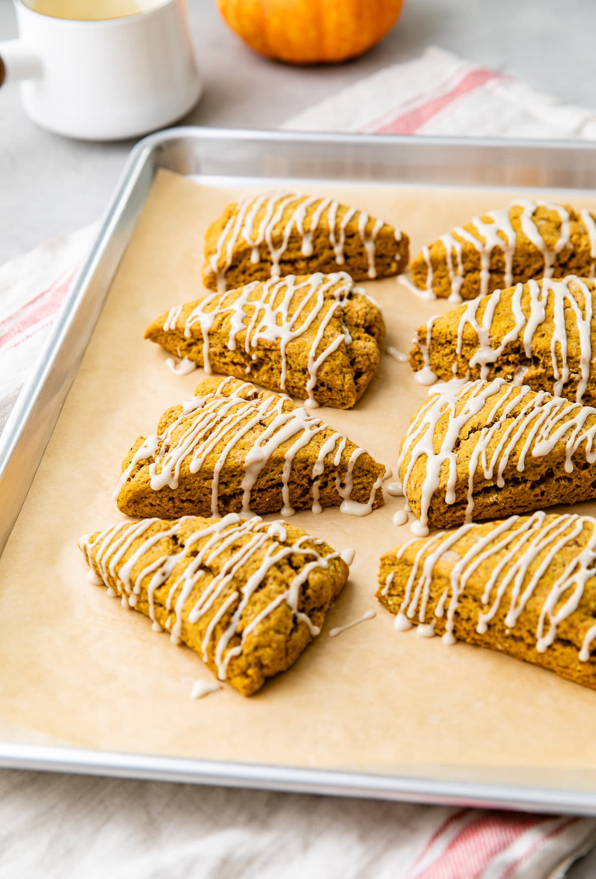 side angle view of pumpkin scones with maple glaze on baking sheet.
