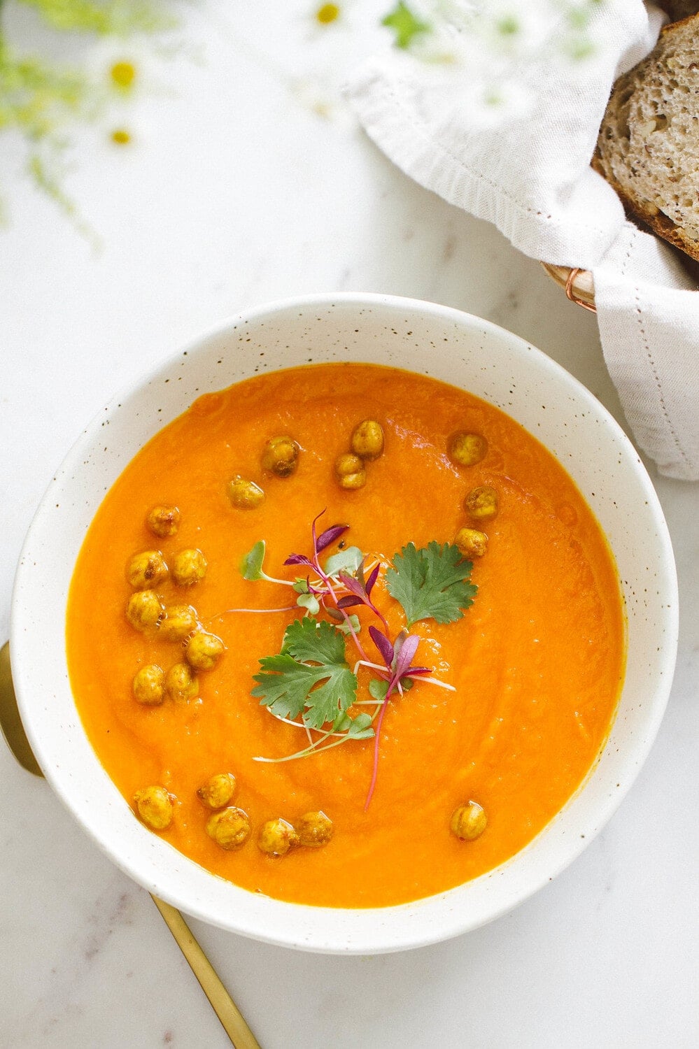 top down view of carrot sweet potato coriander soup with turmeric roasted chickpeas in a bowl.