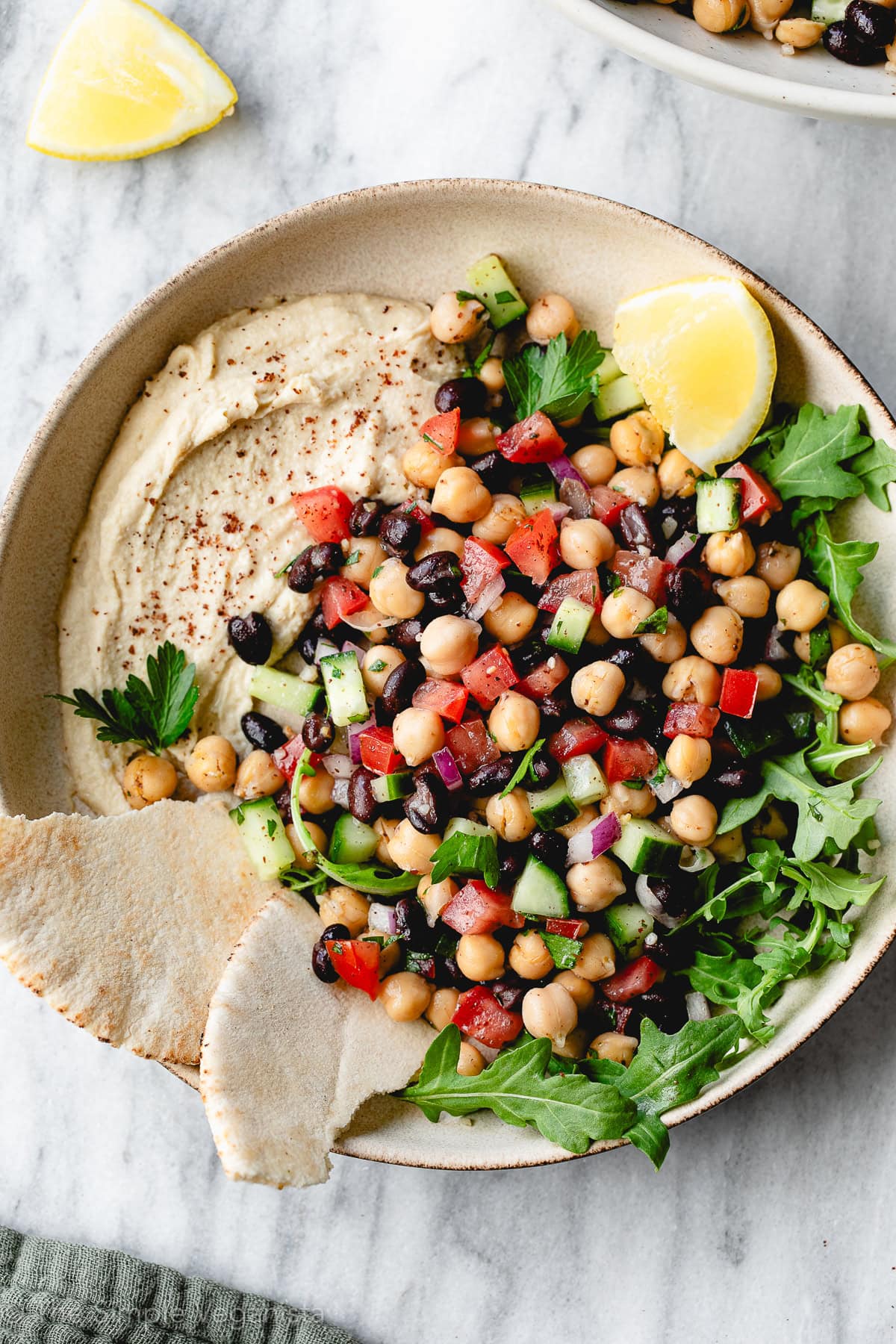 Balela salad served as a healthy Mediterranean side dish with hummus, arugula, and warm pita bread.