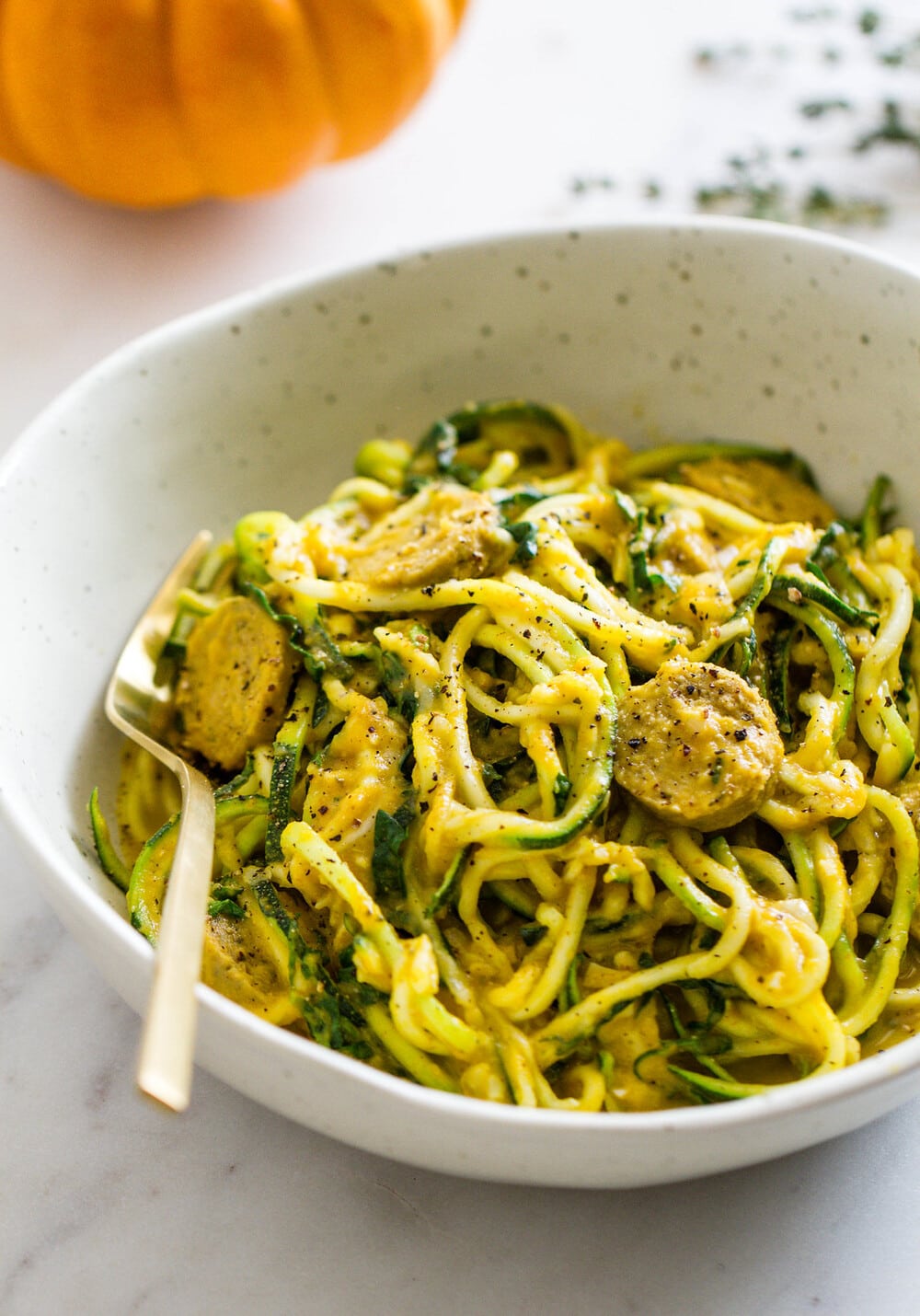 side angle view of creamy pumpkin sauce with kale and mushrooms, tossed with zucchini noodles.