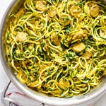 top down view of a pan with cooked zucchini noodles tossed with creamy pumpkin sauce, kale and mushrooms.