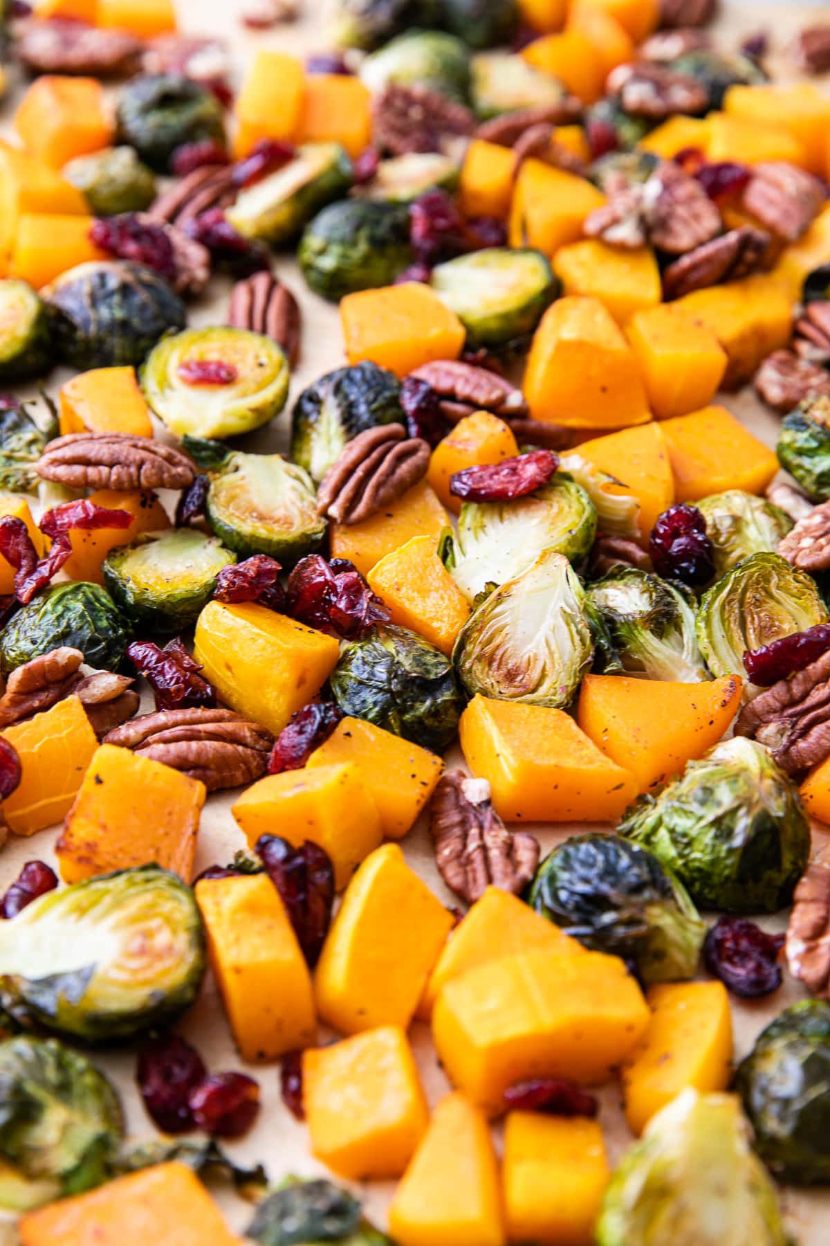 side angle view of freshly roasted brussels sprouts and butternut squash on a baking sheet.