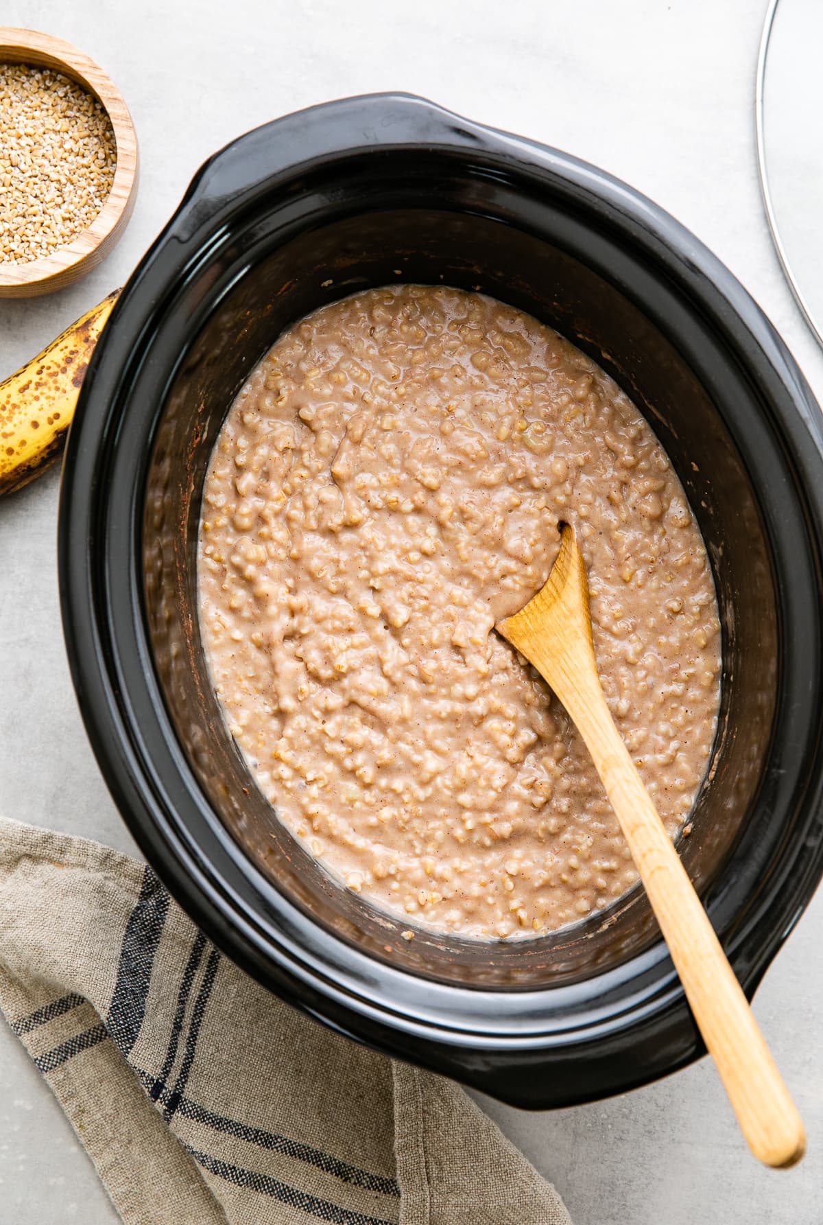 top down view of freshly made banana overnight steel cut oats in the bowl of a slow cooker.