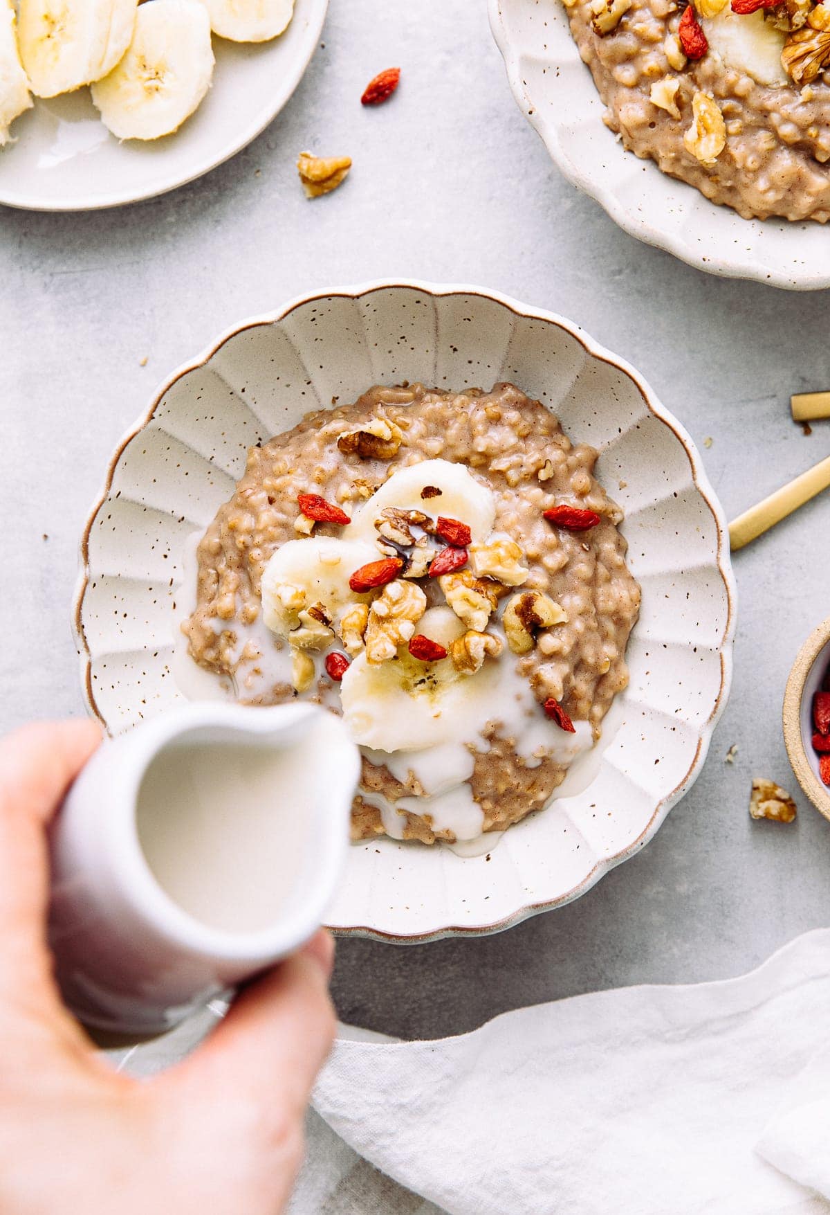 top down view of overnight steel-cup oats oatmeal in a bowl with items surrounding.