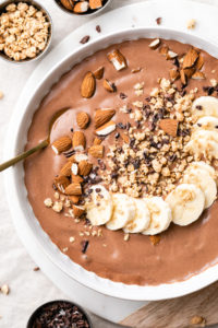 top down view of chocolate almond butter smoothie in a bowl with items surrounding.