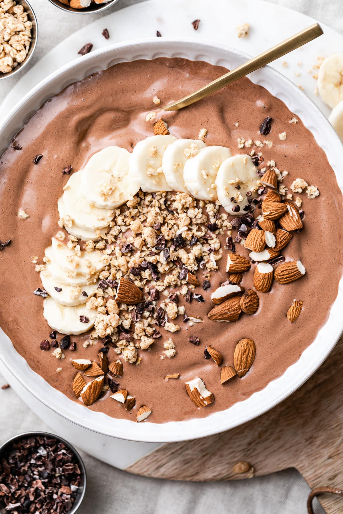 top down view of chocolate almond butter smoothie in a bowl with items surrounding.