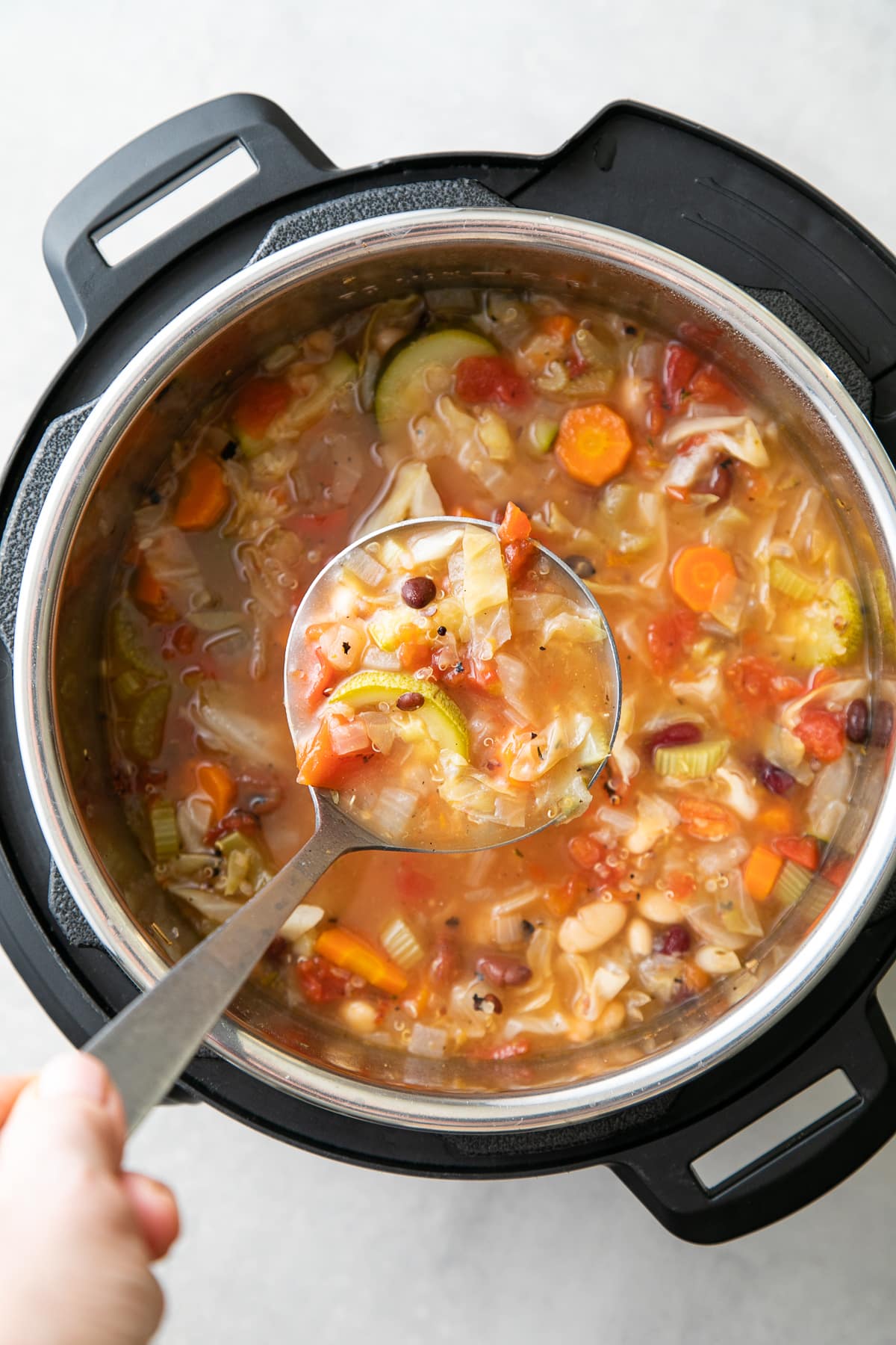 top down view of ladle filled with vegetable quinoa soup.