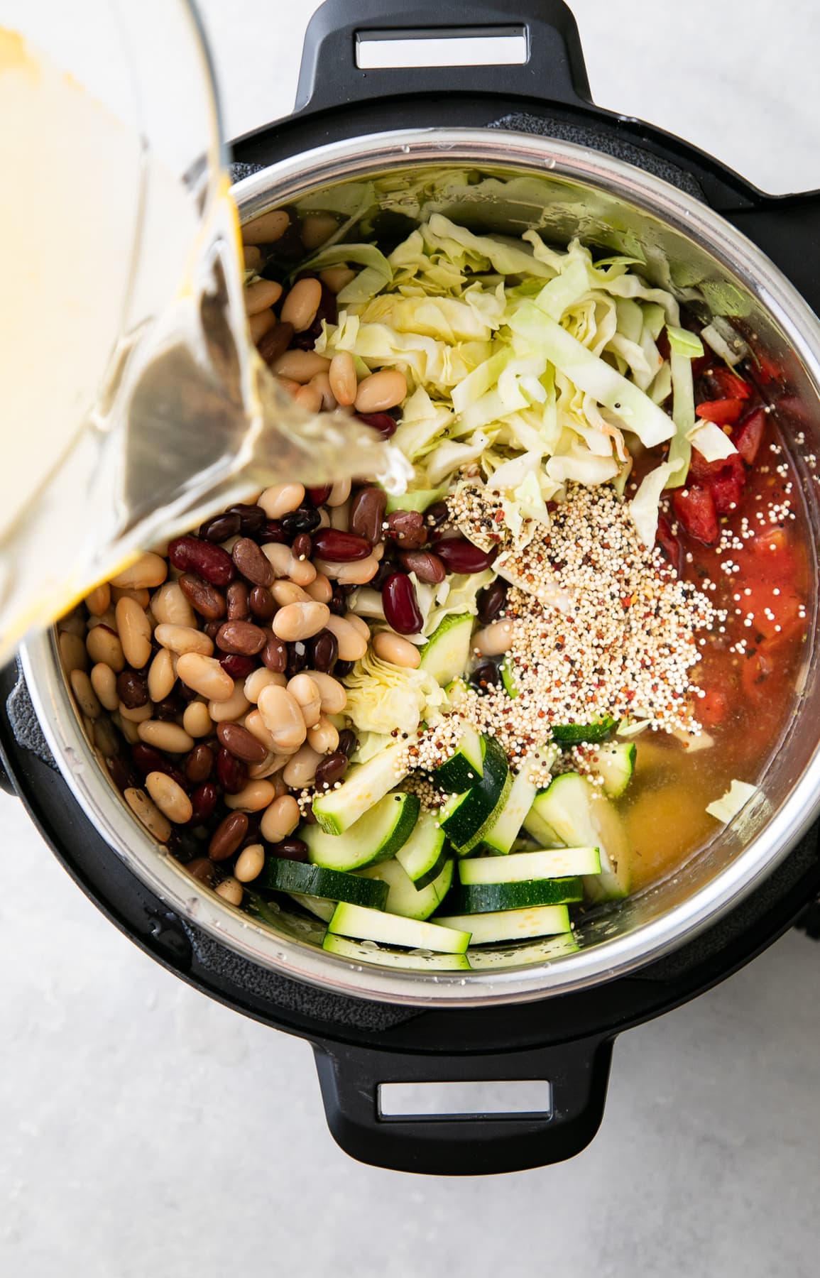 top down view showing the process of adding liquids to soup ingredients before cooking.