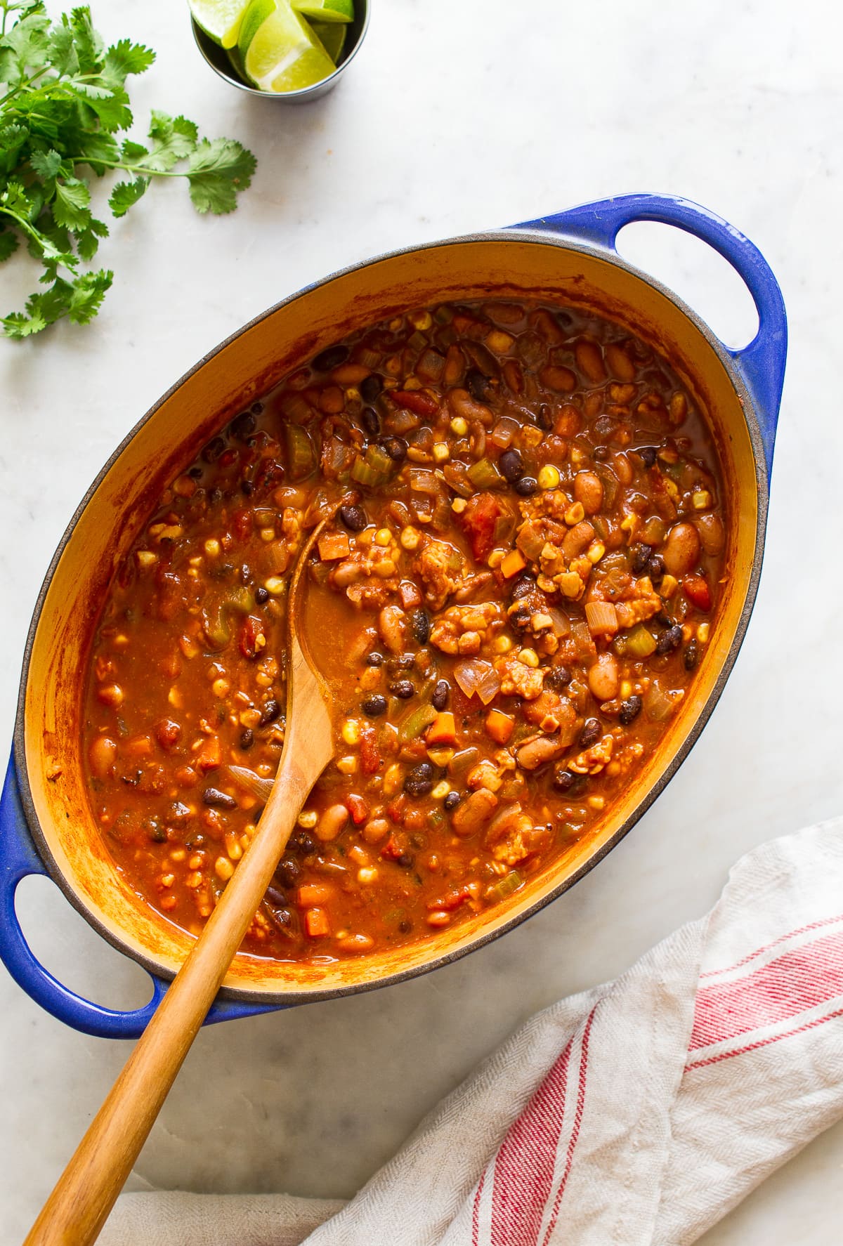 top down view of freshly made vegetable chili in a dutch oven with wooden spoon.