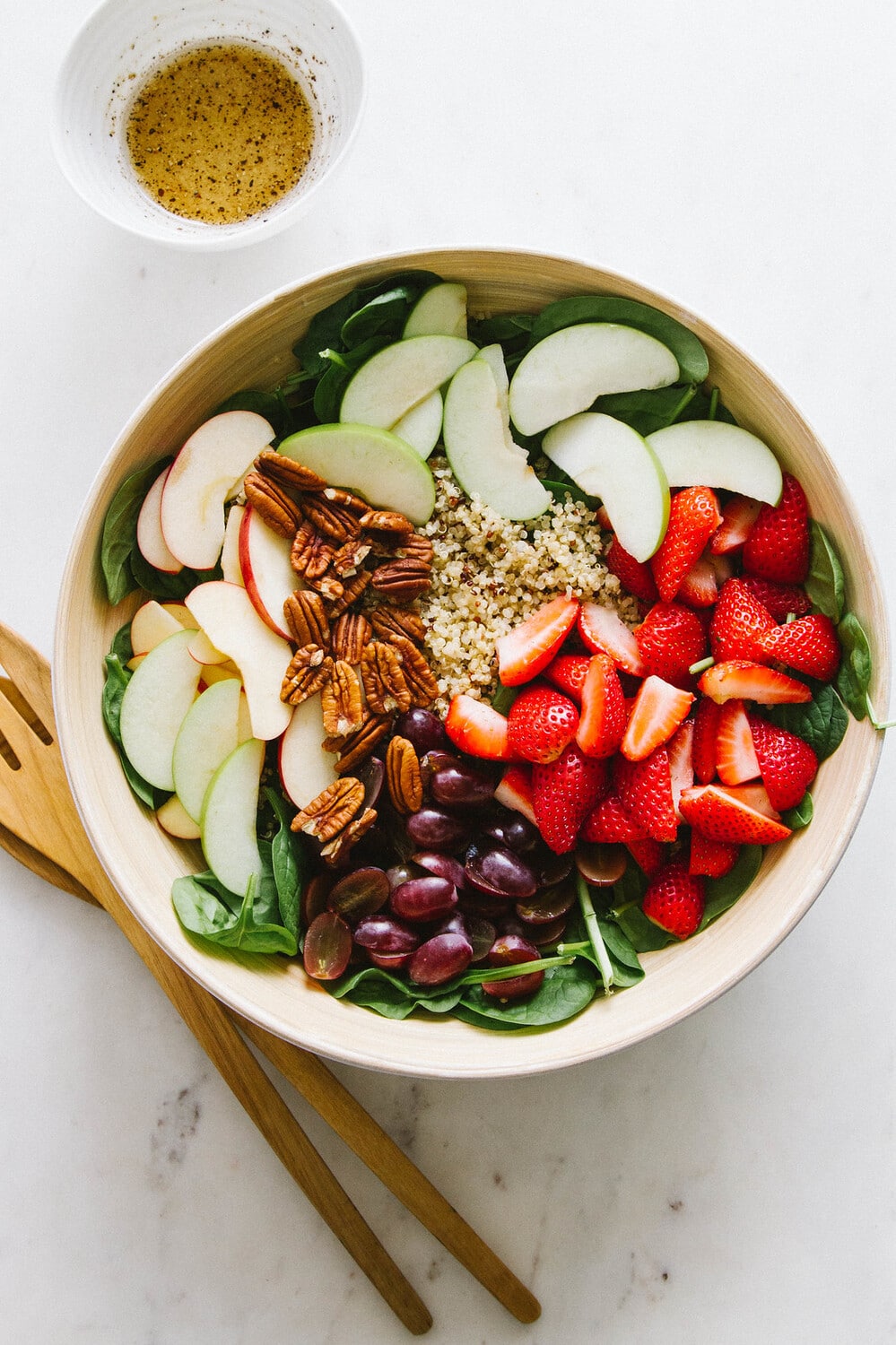 top down view of a large serving bowl filled with the prepped spinach salad ingredients before mixing.