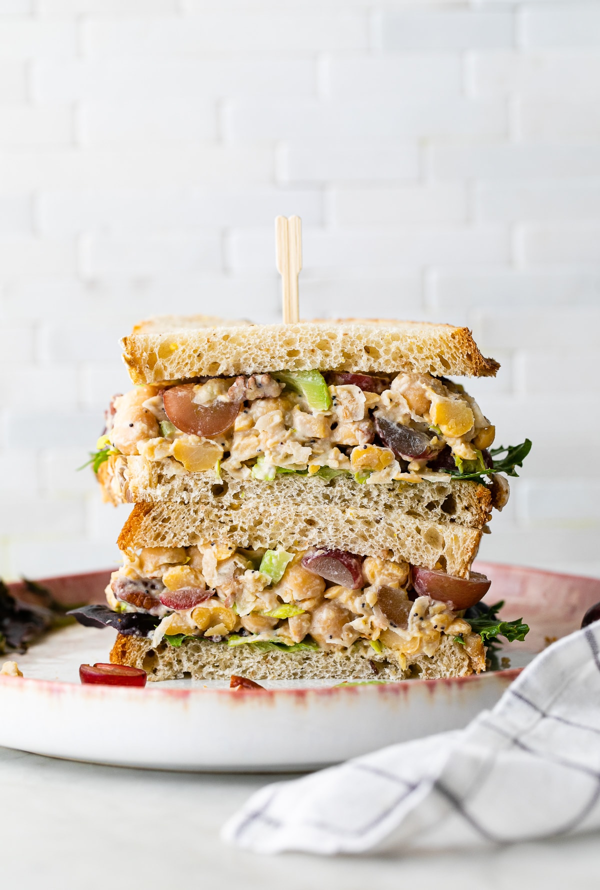 head on view of chickpea chicken salad sandwich sliced in half and stacked.