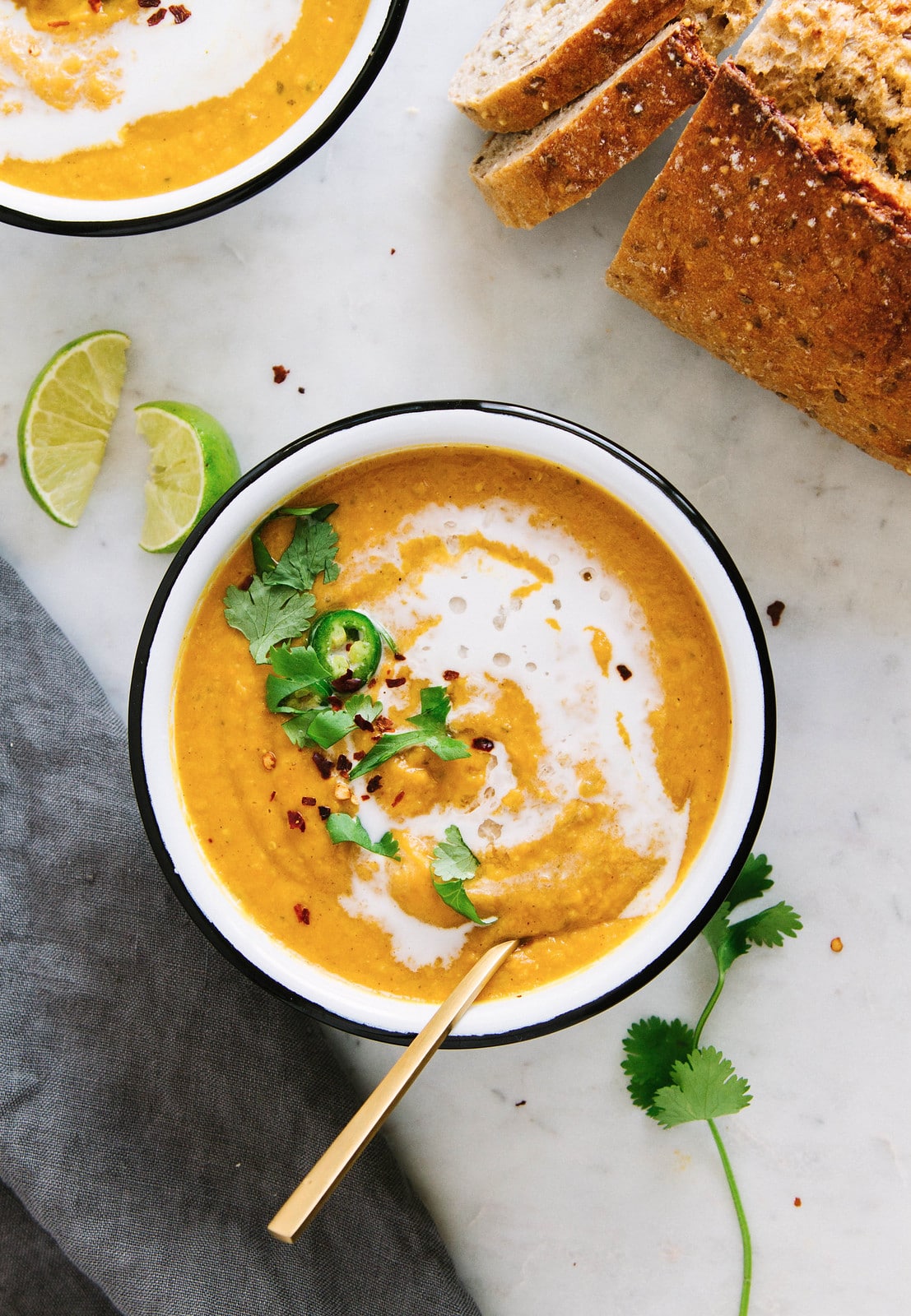 top down view of a bowl filled with a serving of curry sweet potato and red lentil soup with items surrounding.