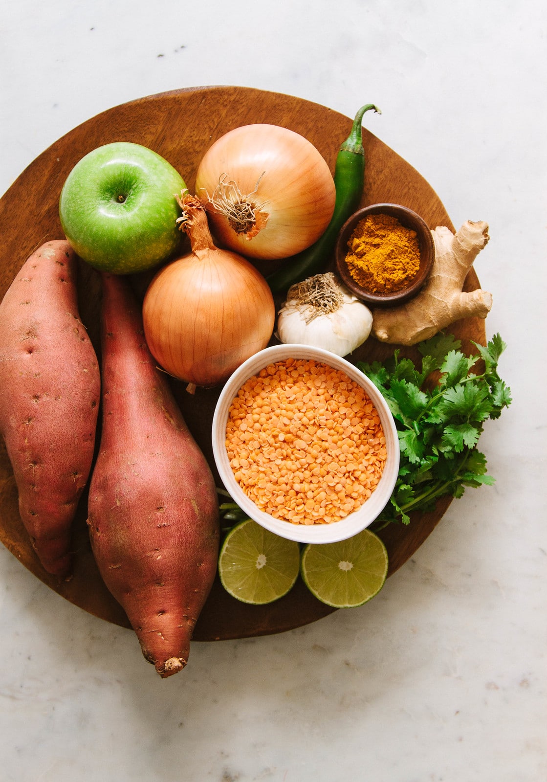 curry sweet potato and red lentil ingredients on a wooden plate.