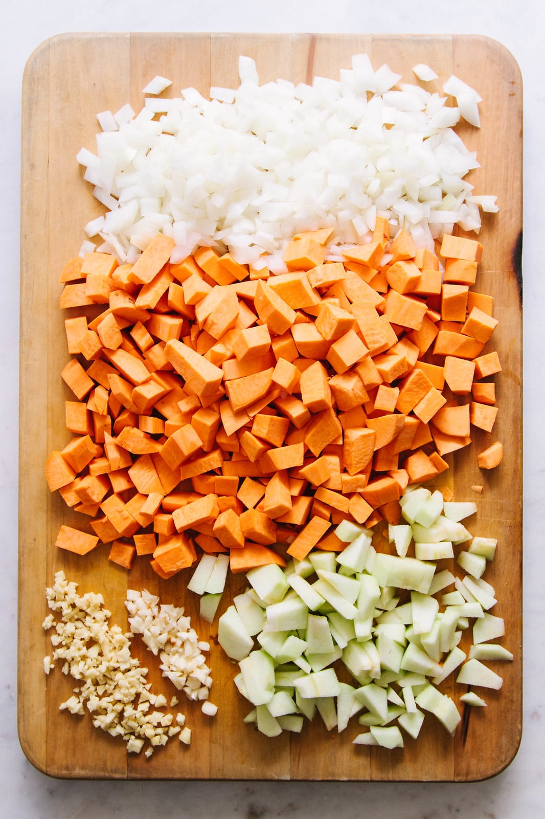 top down view of prepped veggies on a wooden cutting board.