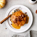 top down view of vegan pumpkin pancakes with pure maple syrup on a plate.