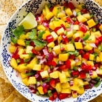 top down view of fresh mango salsa in a bowl surrounded with tortilla chips.