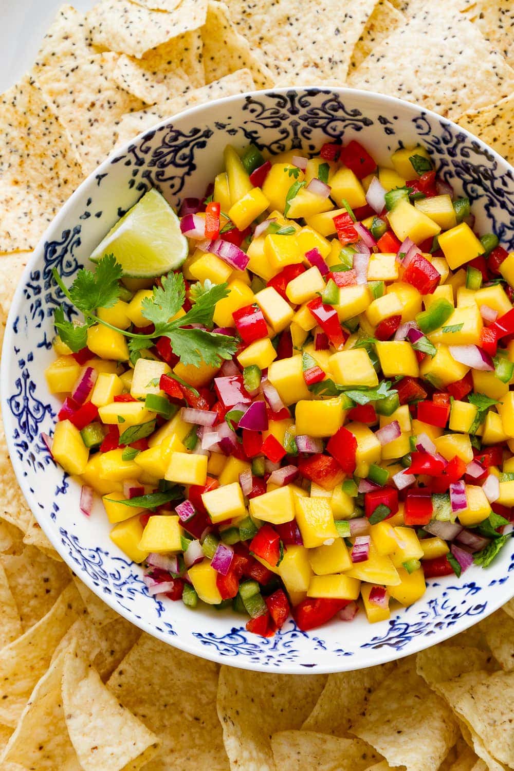 top down view of fresh mango salsa in a bowl surrounded with tortilla chips.