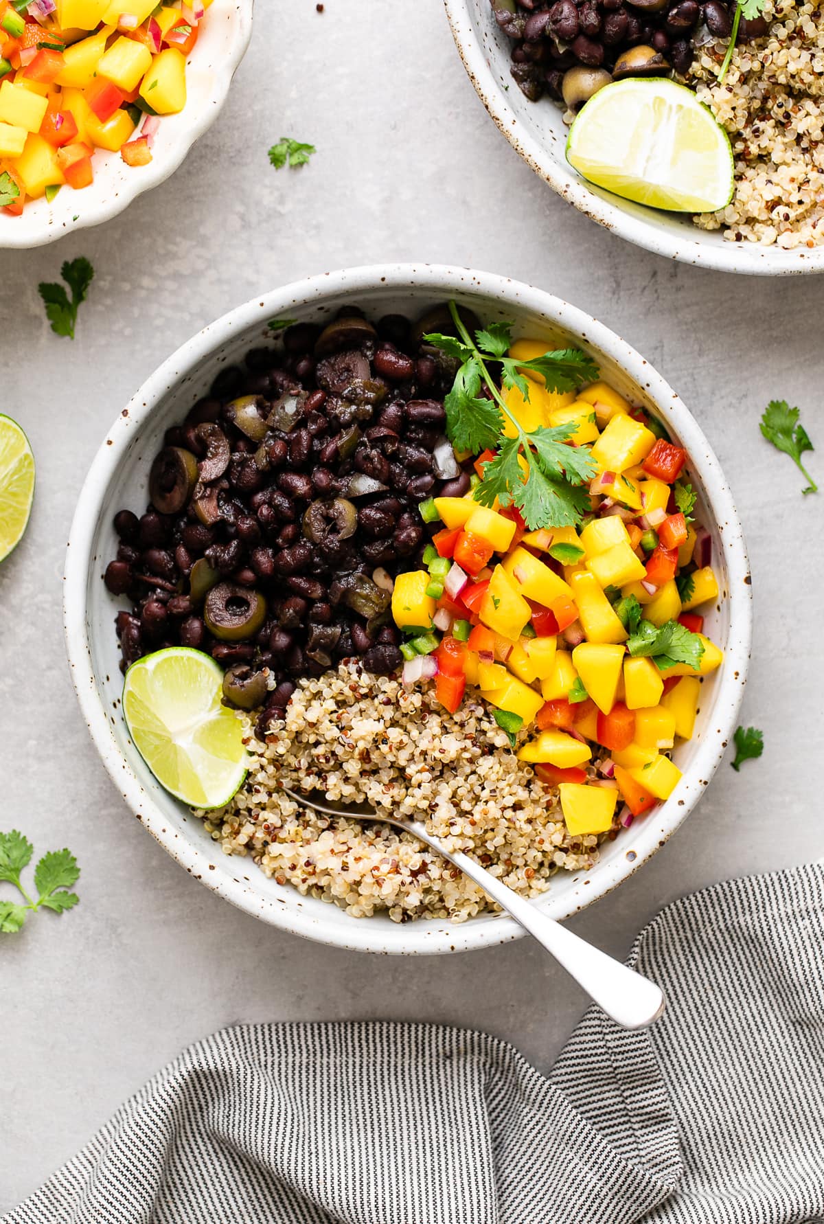 top down view of bowl with serving of cuban black bean mango bowl with quinoa with items surrounding.