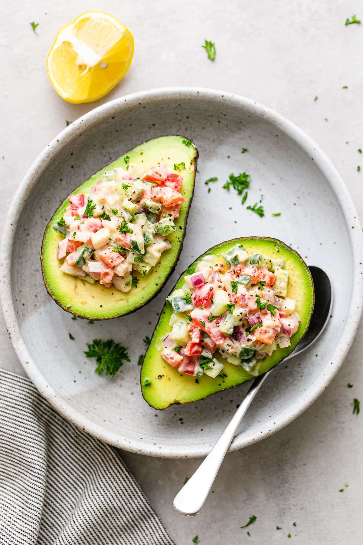 top down view of stuffed avocados in a shallow bowl with spoon.