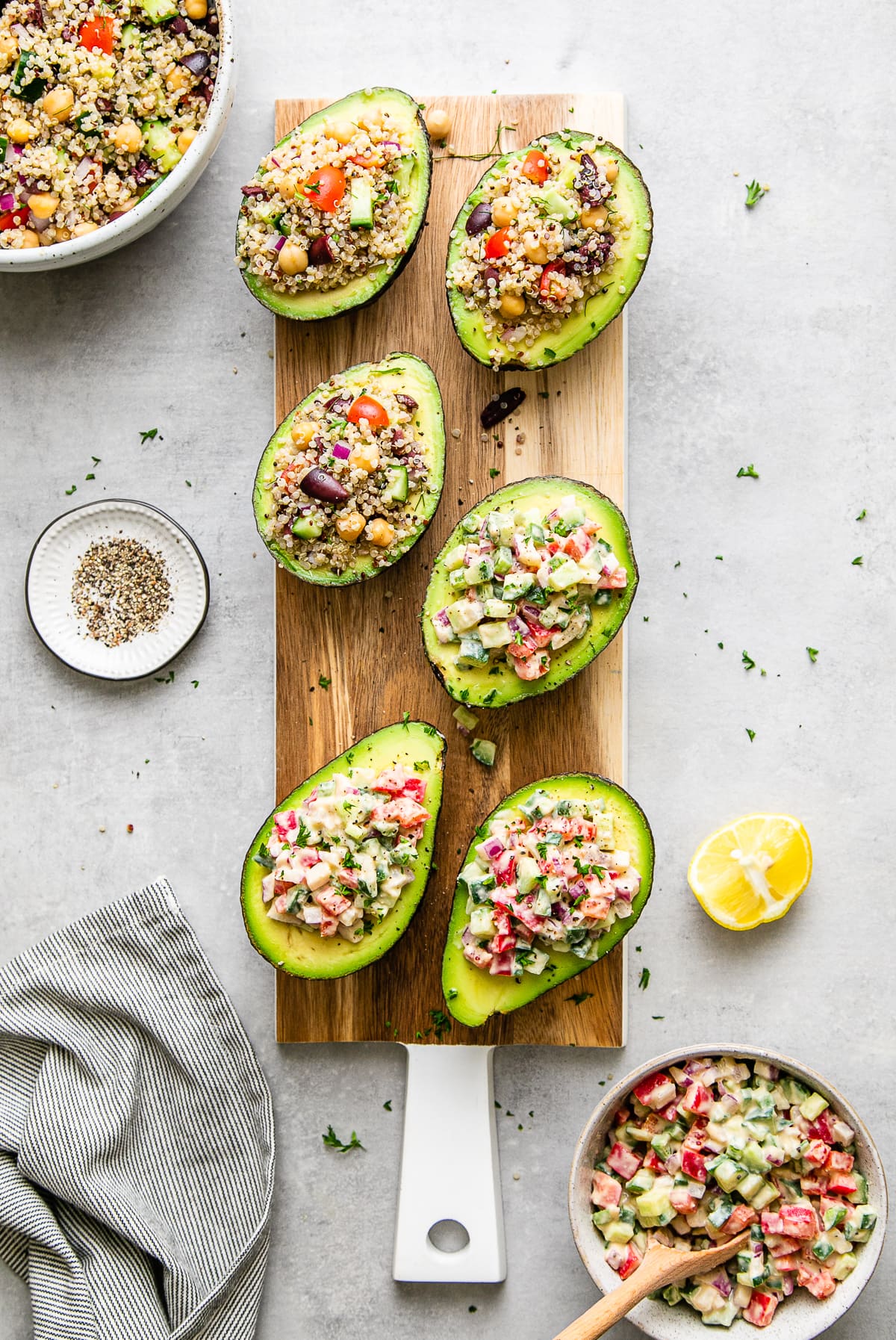 top down view of stuffed avocados on serving board with items surrounding.