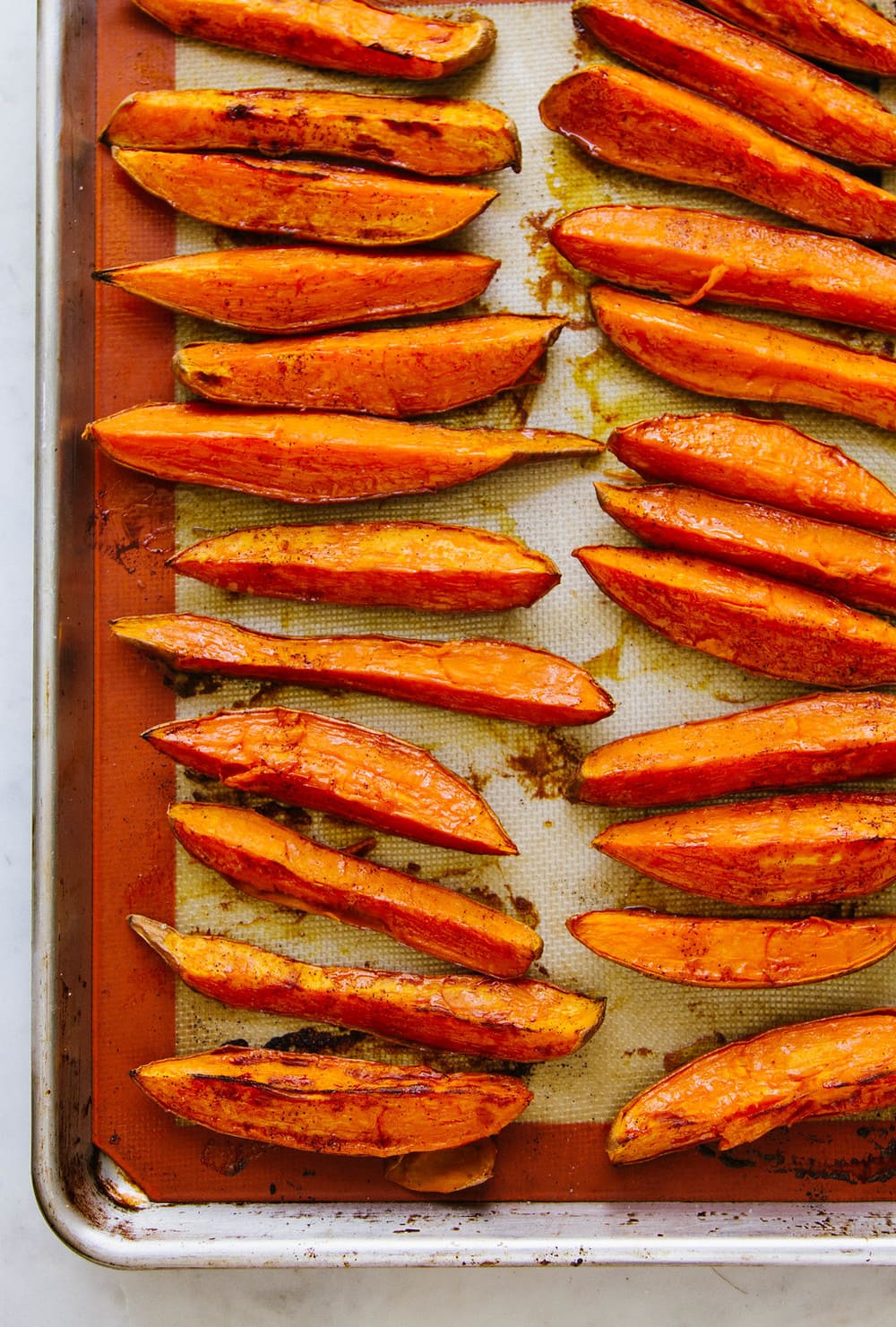 top down view of freshly baked sweet potatos on a rimmed baking sheet just pulled from the oven