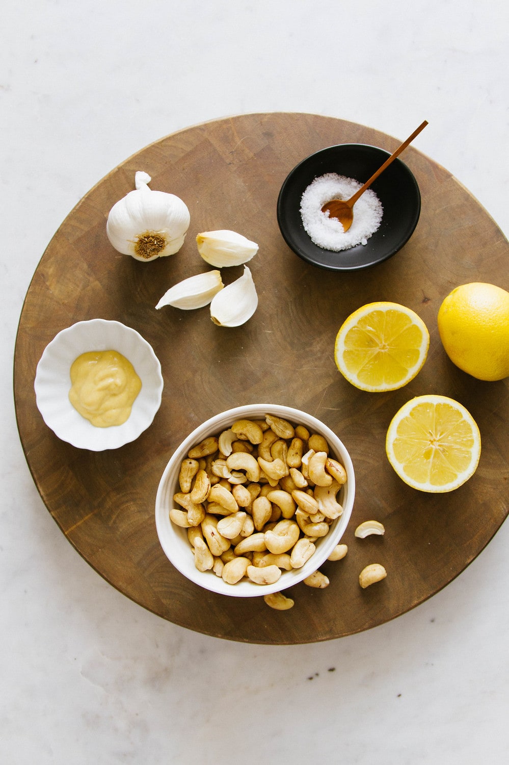 top down view of ingredients to make vegan aioli on a round wooden cutting board